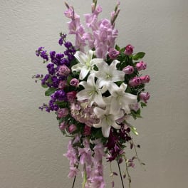 Tall standing floral spray with white lilies, pink roses, and purple blooms