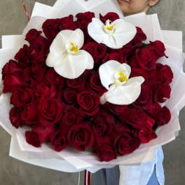 Bouquet of red roses with three white orchids wrapped in white paper