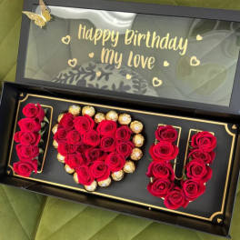 Boxed red roses arranged with chocolates and a birthday message