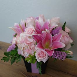 Pink lilies and roses arranged in a black box