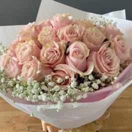 Bouquet of pale pink roses with white baby's breath in pink and white wrap