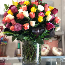 Mixed roses in a clear glass vase with dark ribbon wrap
