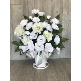 White floral arrangement in a white vase with ribbon