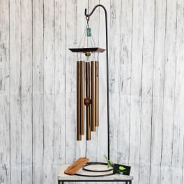 Copper wind chime hanging from a black stand
