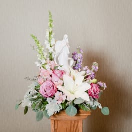 Pink and white floral arrangement with a white angel figurine