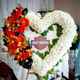 Heart-shaped floral tribute with white chrysanthemums and orange-red flowers