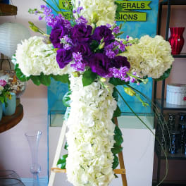 Cross-shaped floral tribute with white hydrangeas and purple lisianthus
