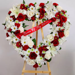 Heart-shaped floral wreath on an easel with a red ribbon
