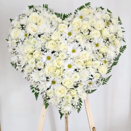 Heart-shaped arrangement of white roses and daisies on a stand