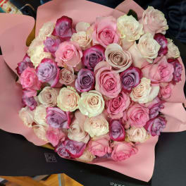 Large bouquet of pink, white, and lavender roses wrapped in pink paper