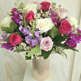 Bouquet of pink, white, and purple roses in a tall vase