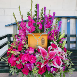 Pink floral arrangement around a wooden religious plaque on a bench