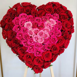 Heart-shaped rose arrangement in red and pink tones on a stand