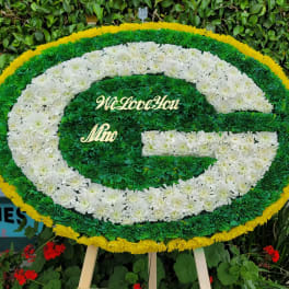 Oval floral tribute in green, white, and yellow with a message in the center