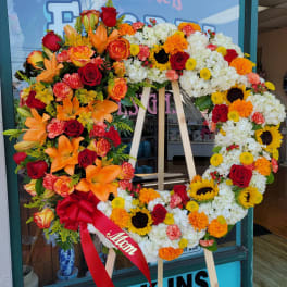 Large floral wreath on an easel with red, orange, yellow, and white flowers