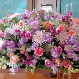 Large pastel floral arrangement with pink and lavender blooms on a table