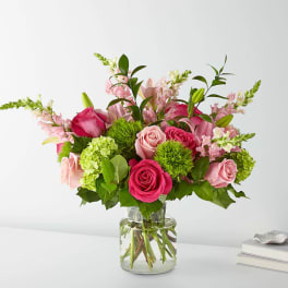 Pink roses and lilies arranged in a clear glass vase