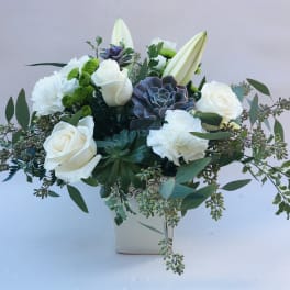 White roses and lilies in a square vase with greenery