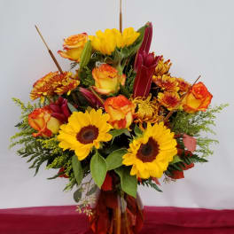 Bouquet of yellow sunflowers and orange roses in a glass vase