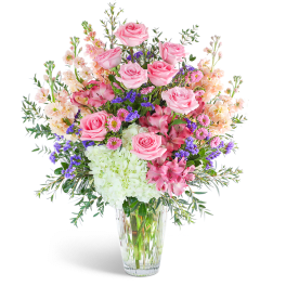 Pink roses and mixed blooms arranged in a clear glass vase