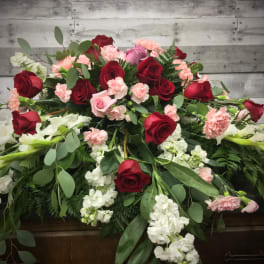 Casket spray with red and pink roses, carnations, and white flowers