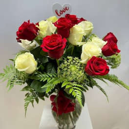 Red and white roses in a glass vase with a heart "love" pick