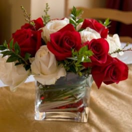 Red and white roses arranged in a clear square glass vase