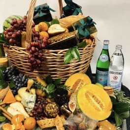 Fruit and snack basket with grapes, melon, bread, cheese, and bottled water