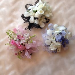 Three small floral corsages with white, pink, and lavender flowers