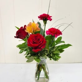 Mixed bouquet of red roses and pink carnations in a clear glass vase