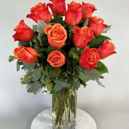 Arrangement of orange roses in a clear glass vase on a round white table