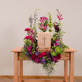 Floral wreath around a wooden cross on a table