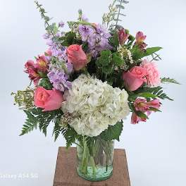 Mixed bouquet of pink roses, purple stock and white hydrangea in a clear glass vase