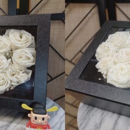 Black square boxes filled with white roses arranged in heart shapes