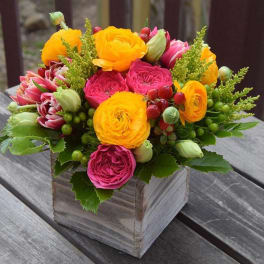 Bright mixed bouquet in a wooden box with yellow and pink blooms
