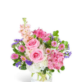 Pink roses and mixed flowers in a clear glass vase