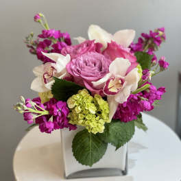 Pink and white floral arrangement in a square glass vase