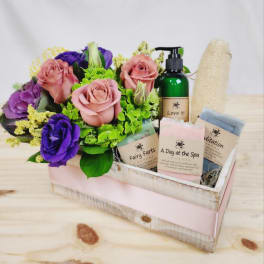 Pink and purple roses in a wooden gift tray with spa items