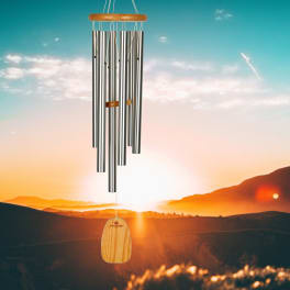 Metal wind chime with a wooden top and clapper hanging outdoors