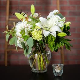 White lilies and mixed white flowers in a glass vase