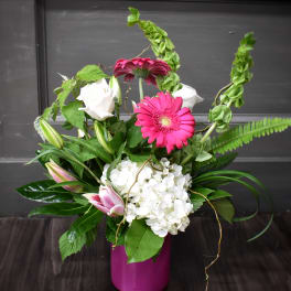 Pink gerbera daisies and white roses in a magenta vase