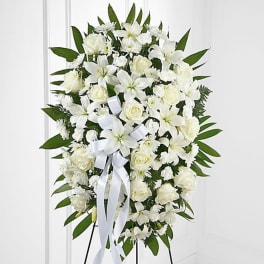White funeral spray with roses and lilies on a stand