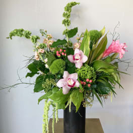Tall floral arrangement with pink orchids in a black vase