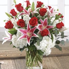 Bouquet of red roses and pink lilies in a clear glass vase
