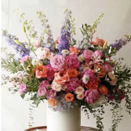 Large mixed bouquet in a white vase with pink, orange, and purple flowers