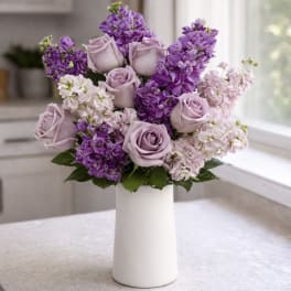 Lavender roses and purple flowers in a white vase