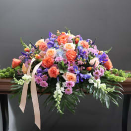 Large pastel floral spray with roses, carnations, and purple blooms