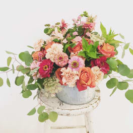 Mixed bouquet of pink, peach, and white flowers in a metal bucket