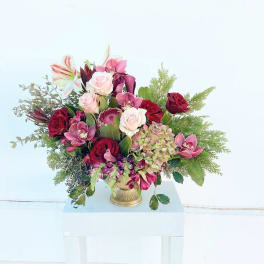 Mixed bouquet of pink and red flowers in a gold vase