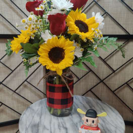 Bouquet of sunflowers, red roses, and white daisies in a glass jar